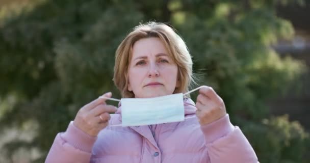 Senior Woman neemt het op tegen Medical Mask. Ademt diep en kijkt naar de camera op Groene Achtergrond. Gezondheidszorg en medisch concept — Stockvideo