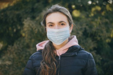 Salgın sırasında koruyucu takan hasta bir kız. Güzel beyaz kız dışarıda tıbbi maske takıyor. Coronavirus COVID-19 salgını sırasında tıbbi maske takan kız.