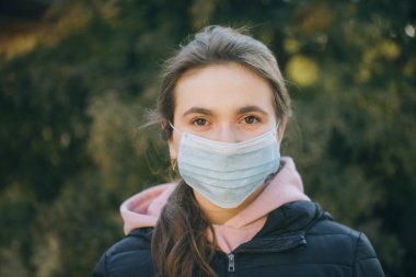 Salgın sırasında koruyucu takan hasta bir kız. Güzel beyaz kız dışarıda tıbbi maske takıyor. Coronavirus COVID-19 salgını sırasında tıbbi maske takan kız.
