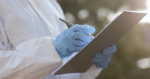 Flickornas hand i en vit handske håller i en penna på ett blankt papper. Läkare kvinna Virolog skriver ett recept eller läkare recept eller diagnostiska resultat koncept. — Stockvideo
