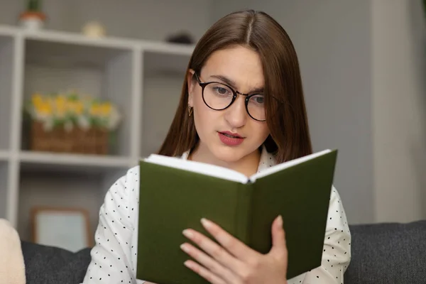 Portret młodego studenta czytającego książkę. Piękna młoda brunetka czyta książkę na łóżku w domu. — Zdjęcie stockowe