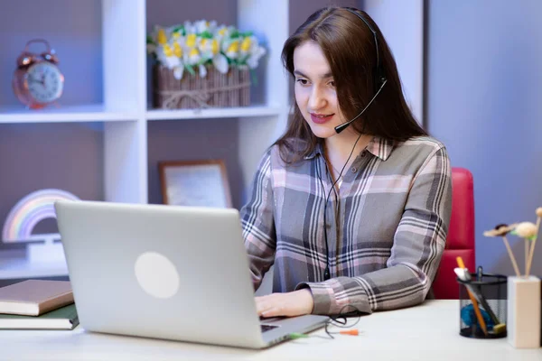 Serious girl student wear headphone study online with internet teacher learn language talk looking at laptop, focused young woman make video call tutoring write notes, teaching concept. — Stock Photo, Image