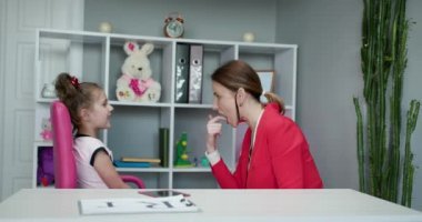 Ses yeteneği sorunu konsepti. Dil terapisti kekeleyen tatlı anaokulu öğrencisi kız çocuğu doğru telaffuz etmeyi öğreniyor. Kekelemede zorluk yaşıyor.