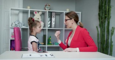 Anaokulu öğrencisi, anne babasıyla ya da konuşma terapisti öğretmeniyle özel ders sırasında konuşma egzersizi yapan küçük bir kız çocuğu. Ses problemi ve telaffuz öğrenme kavramı