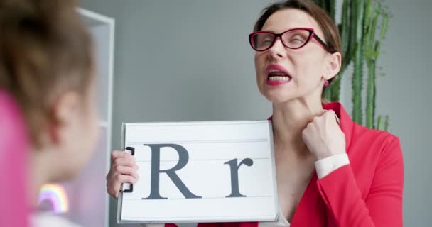 Logopädin hält Buchstabe R und Mädchen Rückansicht. Logopädin bringt den Mädchen bei, den Buchstaben R zu sagen. — Stockvideo