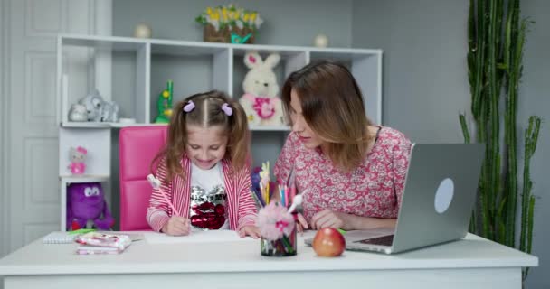 Moeder en kind thuis doen huiswerk online. Online onderwijs op afstand. Moeder doet huiswerk met haar dochter thuis — Stockvideo