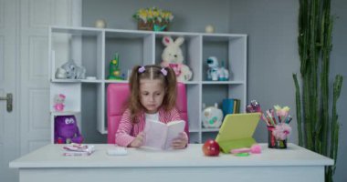Tablet bilgisayar kullanan tatlı bir kız. Evde karantinada dijital tablet üzerinde uzaktan ödev yapan küçük bir çocuk..