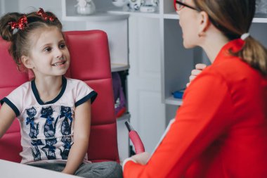 Komik çocuk anaokulu öğrencisi konuşma terapisti konseptiyle telaffuz öğreniyor, anaokulunda küçük bir çocuk konuşma alıştırması yaparken konuşma alıştırması yapıyor.
