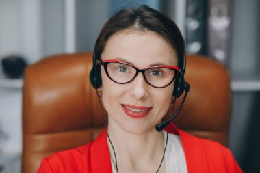Video sohbet işi görüşmesi ya da online öğretmen konsepti olan uzak dil kursu. Mutlu genç kadın konferans görüşmesiyle iletişim kuran kulaklık takıyor ev ofisindeki bilgisayara bakıyor.