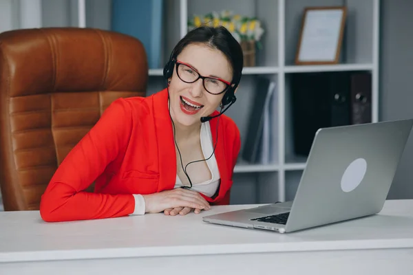 Woman wear headset communicating by conference call speak looking at camera at home office. Video chat job interview or distance language course class with online teacher concept.