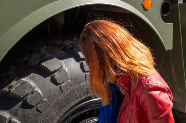 woman looks at the wheel of a military machine. Victory Day May 9, Russia