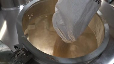 Bira üreticisi poşetten bira demleme tankına malt döker. El yapımı bira..