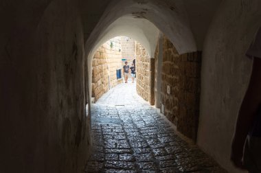 08 10 2019, Jaffa, İsrail. Çocuklu bir adam eski şehrin caddesi boyunca yürüyor. Kemer manzaralı. Veri Işığı.