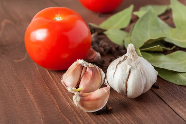 Gewürze und Tomaten auf einem Holztisch. — Stockfoto