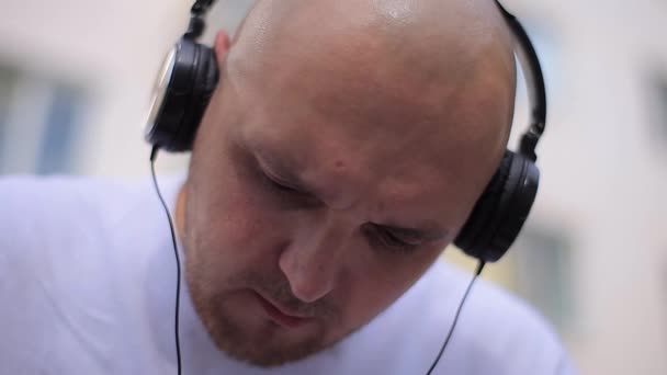 Homem careca com fones de ouvido olhando para baixo — Vídeo de Stock