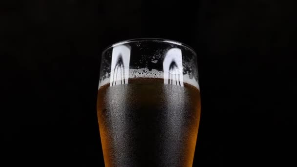 Close-Up van tapbier in beneveld glas op zwarte achtergrond — Stockvideo