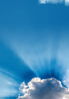 Sun rays bursting through clouds in a blue sky
