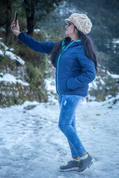 Mujer india tomando selfie sobre un fondo de bosque de invierno cubierto de nieve . — Foto de Stock