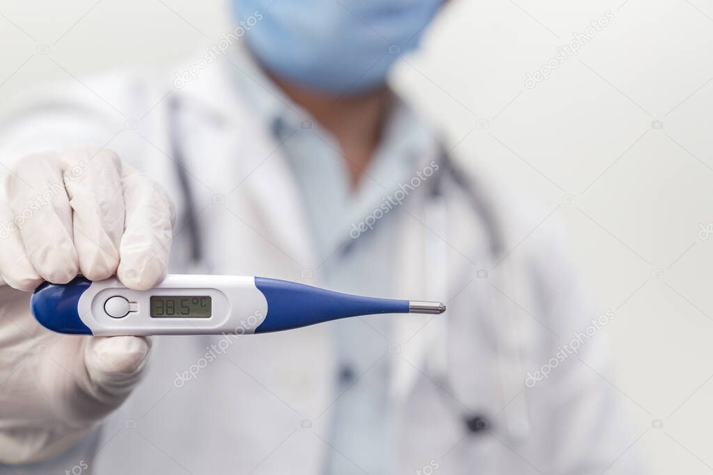Doctor wearing stethoscope holds digital medical thermometer to measure the body temperature, protection from virus, flu & respiratory diseases. Coronavirus (COVID-19) outbreak.