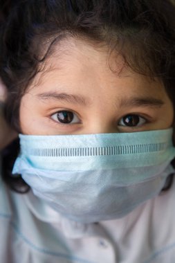 Kendilerini virüsten ve hava kirliliğinden korumak için maske takan Hintli küçük kıza yaklaş. Coronavirus covid-19 salgınının insandan insana yayılmasını engellemek için maske ile önleme.
