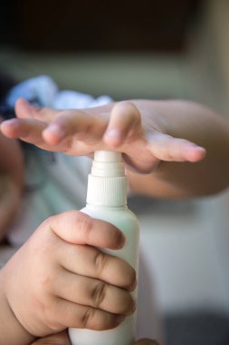 Antiseptik temizleme jeliyle el ele tutuşan çocuk şişesini kapat. Çocuklar Coronavirüsü önlemek için el yıkamak için alkol jeli kullanır, Covid-19. Dünya salgın krizi.