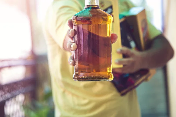 Close up of customer hand showing the whisky liquor bottle as he leave after purchasing liquor from a shop amid ongoing Covid-19 lockdown