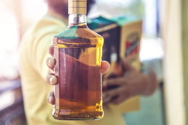 Close up of customer hand showing the whisky liquor bottle as he leave after purchasing liquor from a shop amid ongoing Covid-19 lockdown