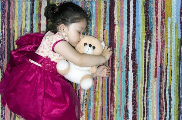 Renkli bir halının üzerinde uyuyan küçük kız.