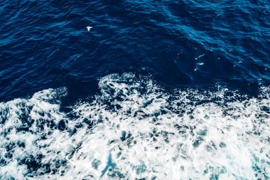 Dalgalı ve köpüklü mavi deniz dokusu. Yukarıdan görüntüle.