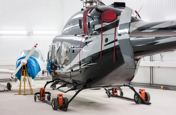 Helicopter and a small sports plane in the hangar