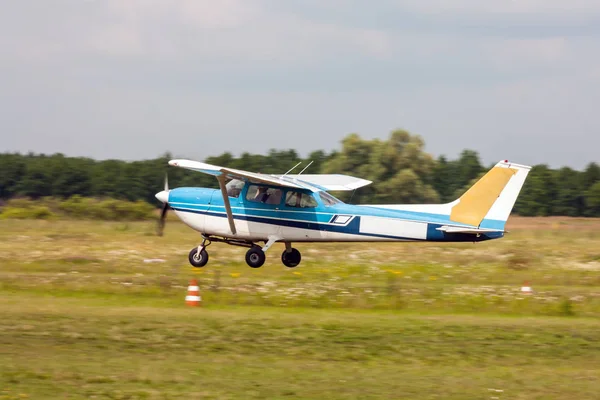 Small private airplane landing on the grass field