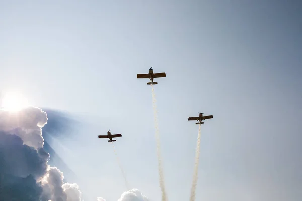 太陽が輝くために積雲雲の背景に煙を排出する飛行中の飛行機のスポーツ — ストック写真