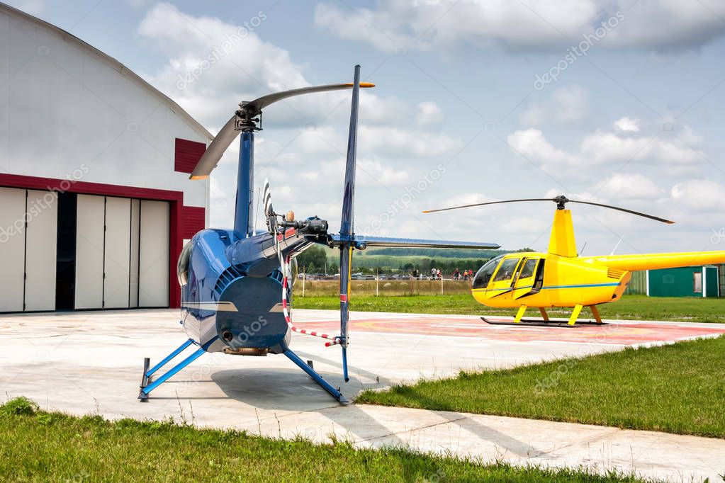 Helipad with two small helicopters beside the hangars