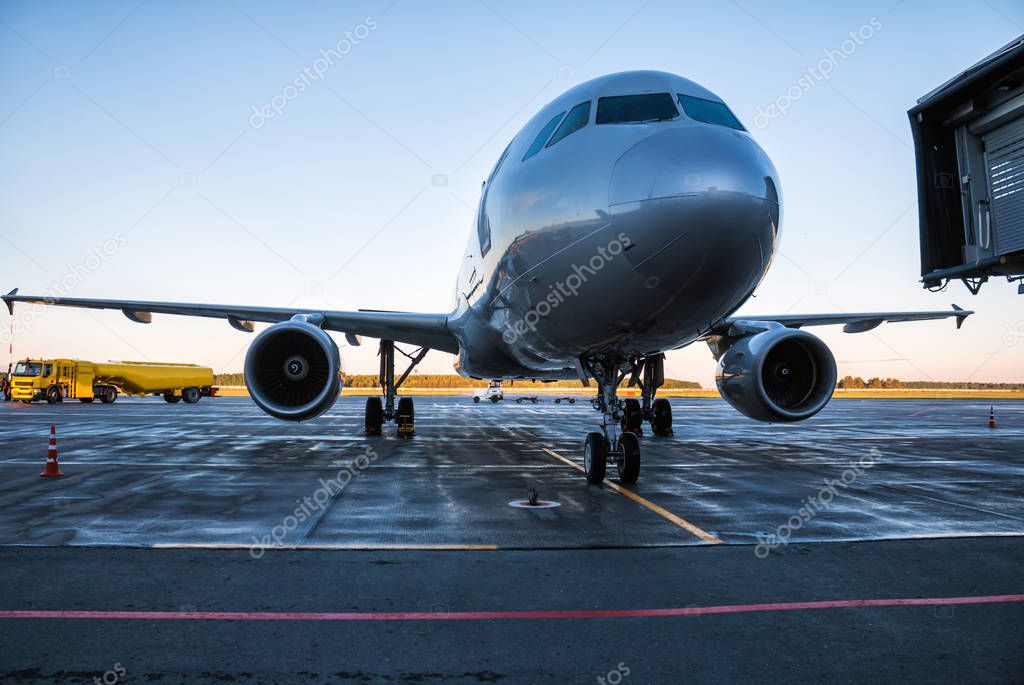 Passenger airplane at the airport apron near the tanker