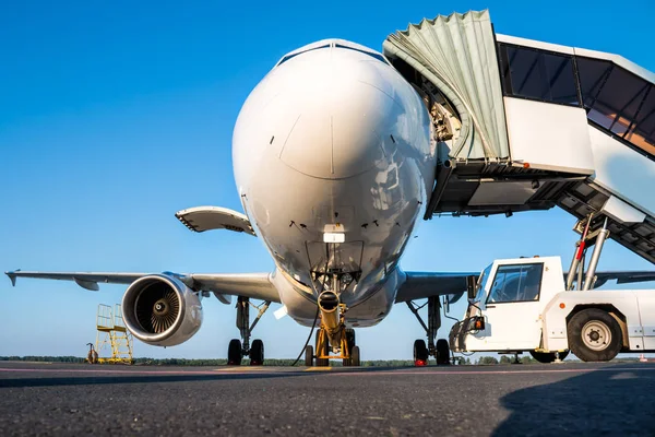 Passenger airplane with open luggage compartment and boarding stairs at the airport apron