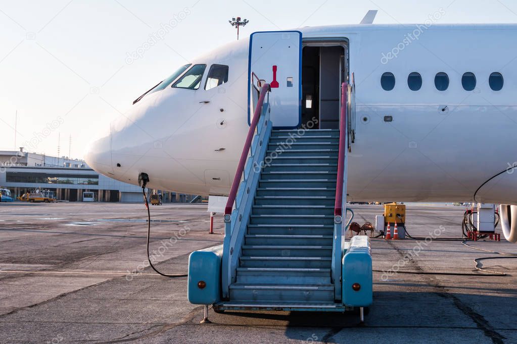 Passenger aircraft with boarding stairs at the airport apron and connected to an external power supply