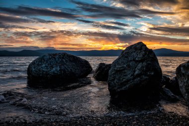 Güzel bir gün batımı zemin karşı gölün kıyısında taşlarının büyük bloklar