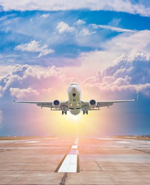 Beyaz yolcu uçakları havaalanından havalanan hava aracıyla güneş ışınlarıyla akşam manzaralı bir gökyüzünün arka planına doğru havalanır.