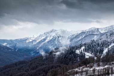 Kış bulutlu bir günde karla kaplı yüksek dağ zirveleri