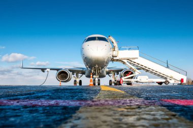 Havaalanı önlüğünün önünde beyaz yolcu uçağı var.