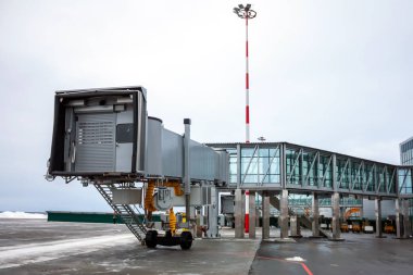 Empty passenger air bridge at the winter airport apron clipart
