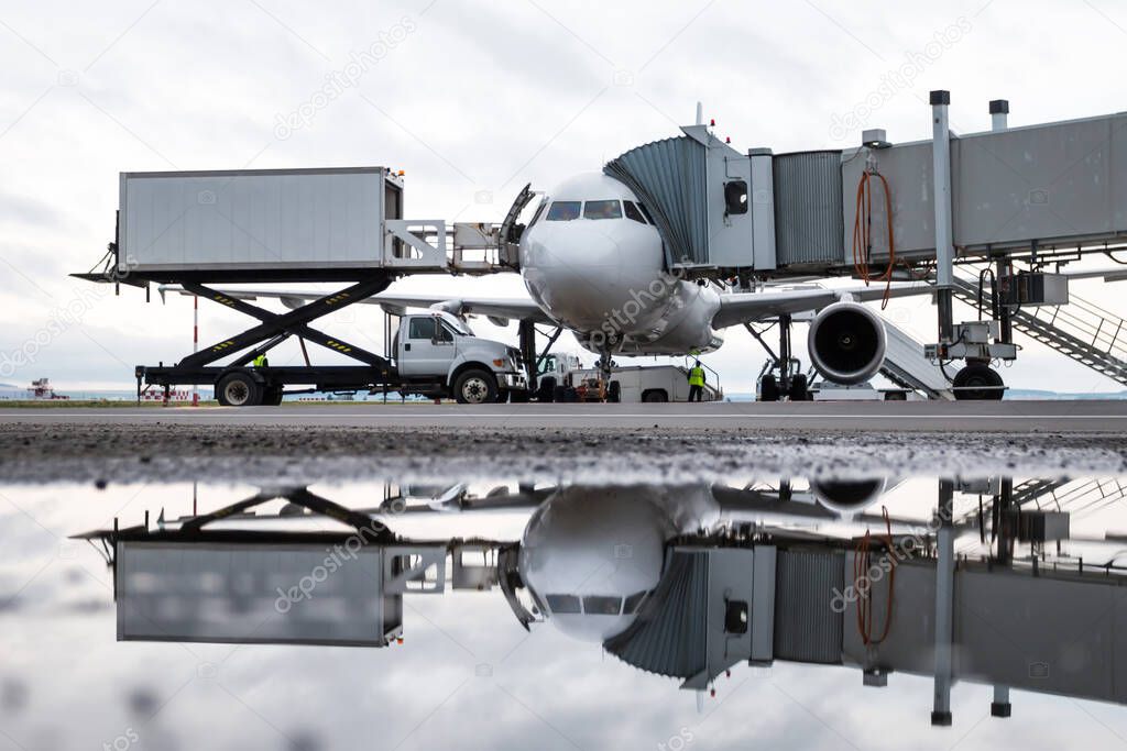 Ground handling of a white passenger aircraft near the air bridge. Loading on-board catering from a truck to an airplane