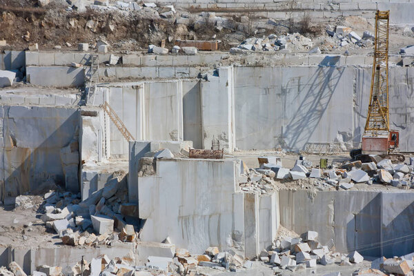Straight walls from quarrying marble blocks in a quarry. Crawler Crane inside a career