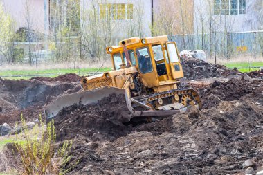 Sarı buldozer inşaat alanında zemini dümdüz ediyor.