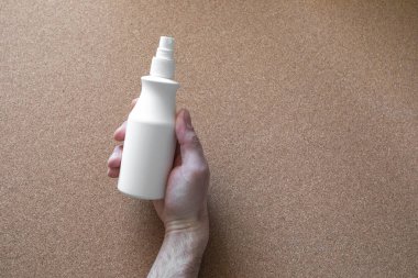 Erkek eli mantar arka planda dezenfektan tutuyor