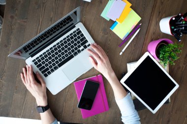 Bilgisayarı, tableti ve telefonu olan bir ofis masası. Dişi eller kalemi tutar. Ofis İşçi Masası