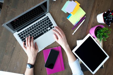 Bilgisayarı, tableti ve telefonu olan bir ofis masası. Dişi eller kalemi tutar. Ofis İşçi Masası