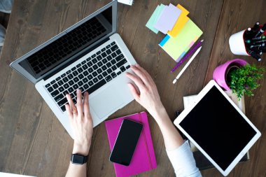 Bilgisayarı, tableti ve telefonu olan bir ofis masası. Dişi eller kalemi tutar. Ofis İşçi Masası