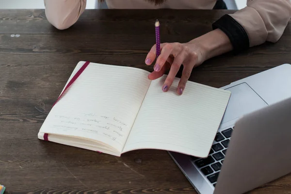 Bilgisayarlı, tabletli bir ofis masası. Kadın ellerinde fuşya renkli bir kalem. Yazmak için sarı çarşaflar, kalemler ve masanın üstündeki saksıda bir çiçek.