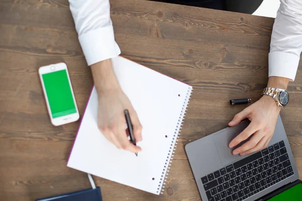 Bilgisayarı, tableti ve telefonu olan bir ofis masası. Erkeklerin elleri akıllı telefon tutuyor. Ofis İşçi Masası